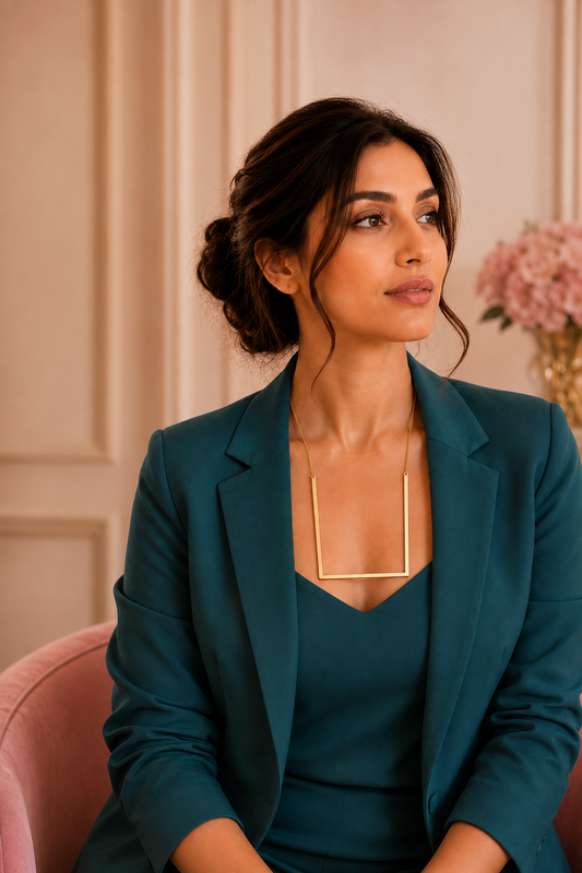 Woman wearing RAVINAAZ Portico Architectural Necklace, a gold-toned mid-length geometric necklace with an open-frame architectural design